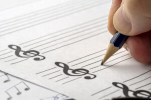 MUSIC COMPOSER WRITING NOTES WITH PENCIL ON THE STAVE. CLOSE UP. COPY SPACE.