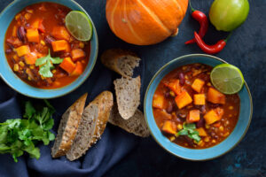 Hot vegan chili with Hokkaido pumpkin from the vegan cuisine with lime and coriander served with slices of a wholemeal roll