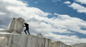 A small black figure pushing a large marble stone. heavy tasks and problems concept. Sisyphean work, task.