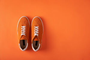 Top view of casual orange suede sneakers on orange background with copy space