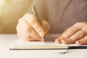 Male hand writing in notebook with pen