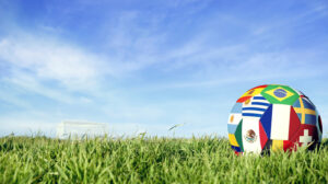 Soccer ball with international country flag of russian sport event groups. Realistic football on goal post field over blue sky background. Includes france, mexico, brazil and more.