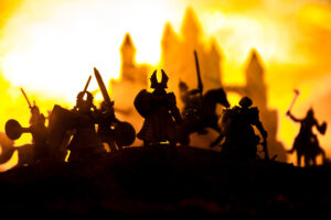Medieval battle scene with cavalry and infantry. Silhouettes of figures as separate objects, fight between warriors on sunset foggy background. Selective focus