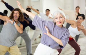 Cheerful old lady learning new modern dance in group dance lesson