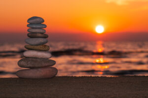 Stacked rocks on the beach with a sunset ocean in the background, Zen Sunset Wallpapers, Pyramid of pebbles on the beach at sunset.