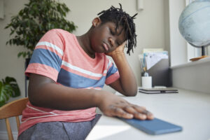 Teenage Boy Taking A Break From Social Media After Abuse And Bullying Laying Mobile Phone Down On Table