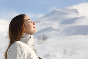 Profile of an explorer woman breathing fresh air in winter with a snowy mountain in the background