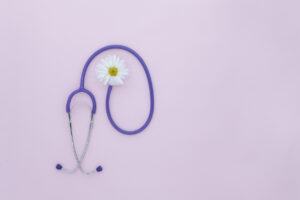Stethoscope, white flower on pink background with copy space. Medical flat lay. International Nurse's Day. International Women's Day. March 8th. creative