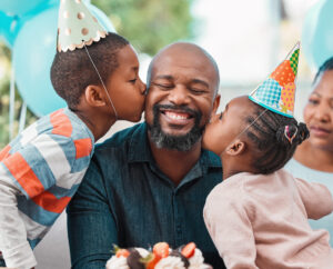 two children kissing Dad on his cheeks during a birthday party