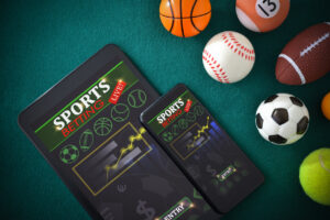 Analysis and online sports betting on mobile devices with application on a table with a green felt mat with objects representative of different sports. Top view.