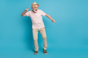 Full size photo of aged man pensioner happy positive smile have fun dance party isolated over blue color background.