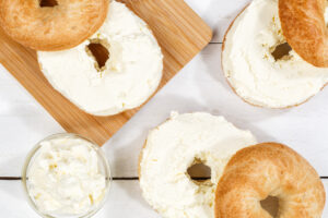 Bagel sandwich with fresh cream cheese for breakfast from above on a wooden board