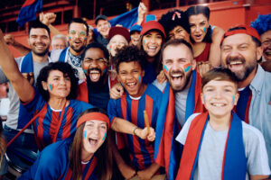 Cheerful fans celebrating the victory of their favorite team at the stadium and looking at camera.