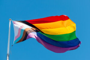 A large Progress Pride Flag flies on a flagpole in Taylor Square, Oxford Street, Darlinghurst, Sydney. This image was taken on a sunny and windy afternoon on 5 April 2025.
