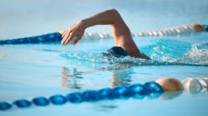 Shot of an unrecognizable young male athlete swimming in an olympic-sized pool