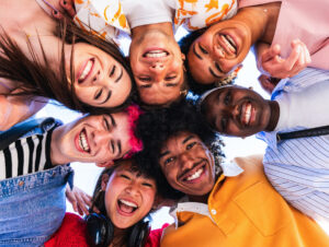 Multiethnic group of young happy friends hanging out in the city - Multiracial group of students meeting and having fun outdoors, concepts about youth, teenage, diversity and lifestyle