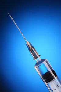 Disposable syringe and needle on the blue background. Macro shot