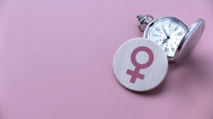 Women symbol over a watch. Healthcare and medical for women. Pink background with copy space.
