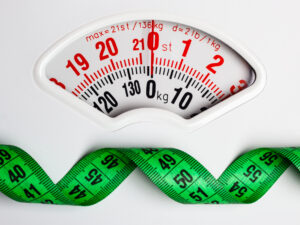 Dieting weightloss slim down concept. Closeup measuring tape on white weight scale copy space text area