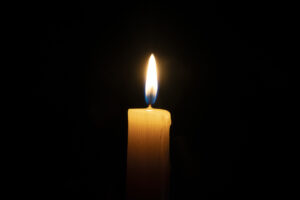 a orange candle burns on a black background with a reflection copy space,