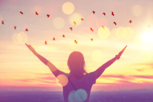 Freedom feel good and travel adventure concept. Copy space of silhouette woman rising hands on sunset sky at top of mountain and bird fly abstract background. Vintage tone filter effect color style.