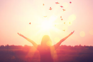 Freedom and feel good concept. Copy space of silhouette woman rising hands on sunset sky double exposure colorful bokeh light and birds fly background. Vintage tone filter effect color style.