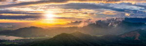 Fog and clouds settle in green forest valleys during a golden sunset.