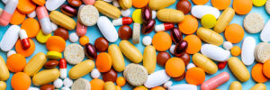 different types of tablets, pills and capsules over blue background. above view. medicine concept. banner template.