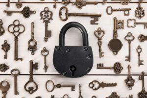 Flat lay composition with padlock and beautiful vintage keys on white wooden table